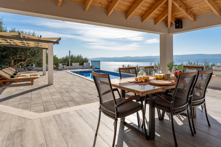 Covered outdoor dining area for 6 people with TV and a barbecue