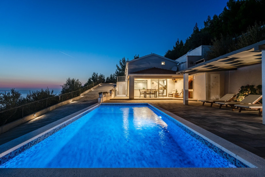 Outdoor dining area, grill and pool area in the evening