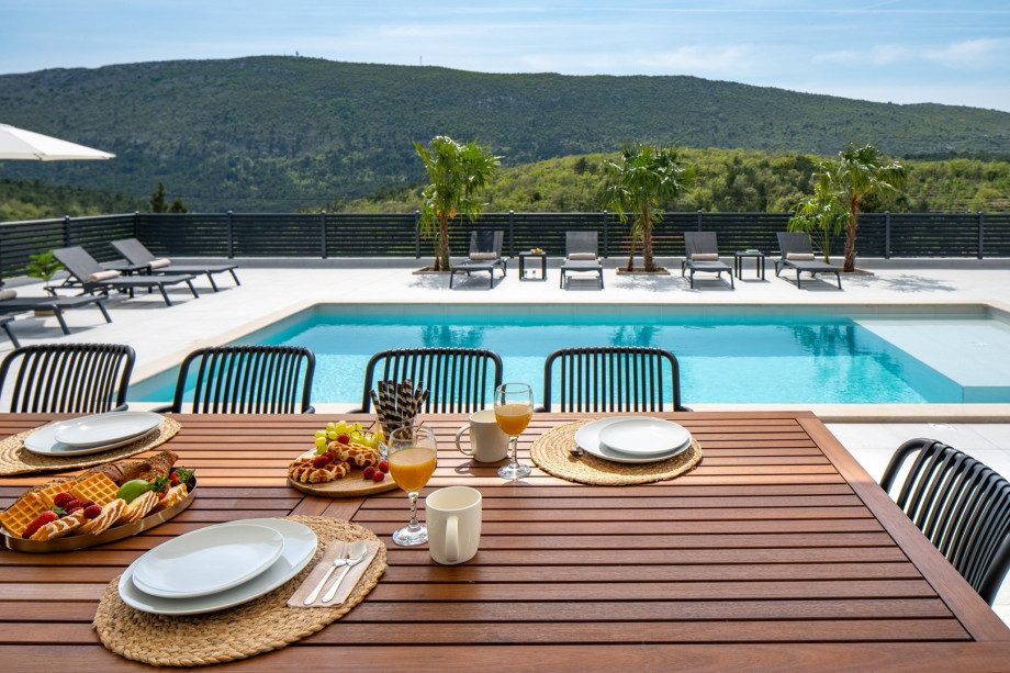 A covered outdoor dining table with seating for ten people