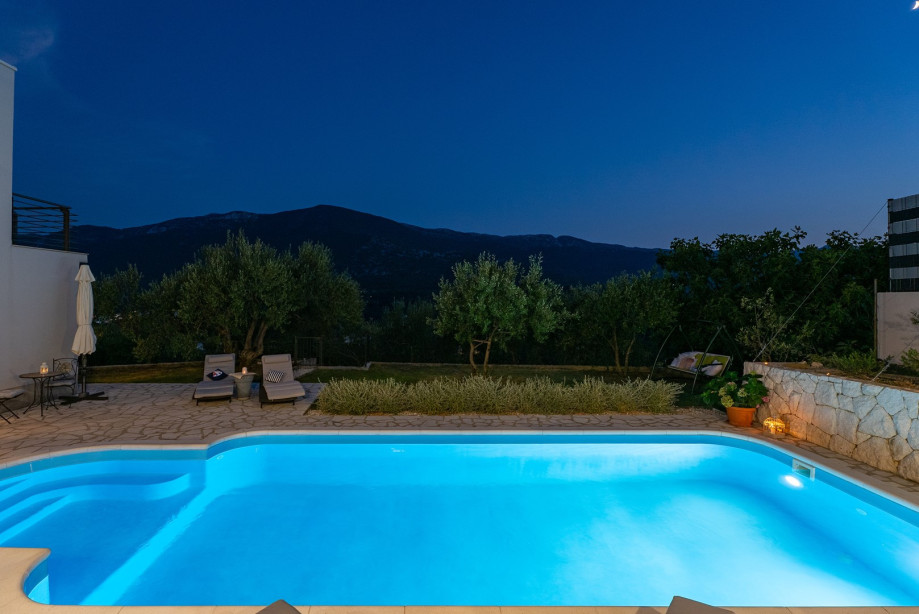 Sun deck area with 4 deck chairs and private pool, at night