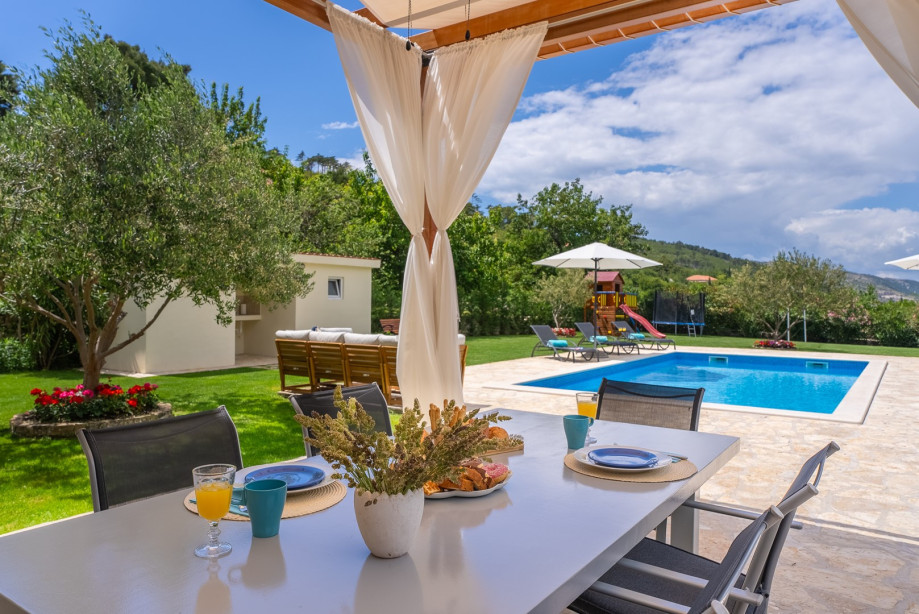 The outdoor dining area is covered and is located in front of the living room.