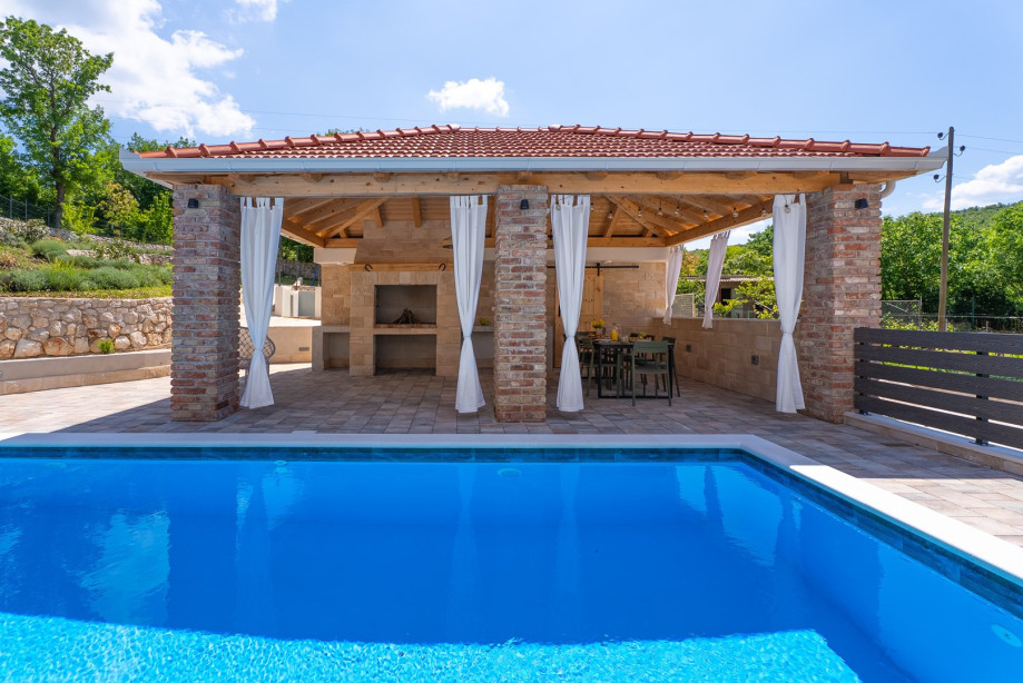 A covered dining area beckons guests to enjoy al fresco meals in style
