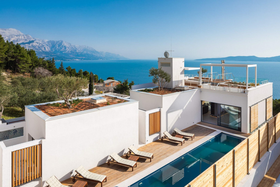 A rooftop area (93 sqm) approachable by elevator or a staircase offers a barbecue, a kitchenette with a fridge, a covered outdoor dining area for 8 people, and a cozy sitting area.