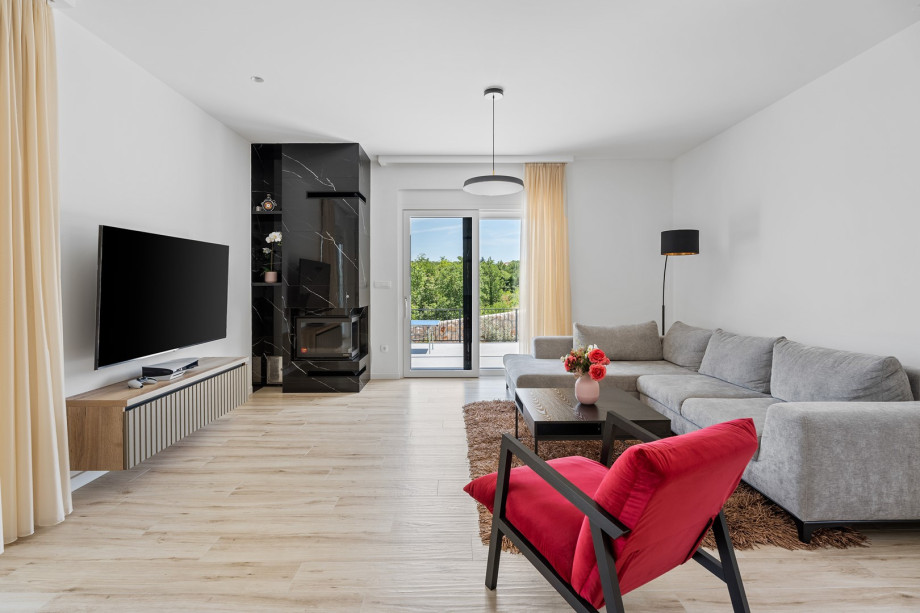 The elegantly furnished living room includes comfortable sofas, a TV, and air conditioning