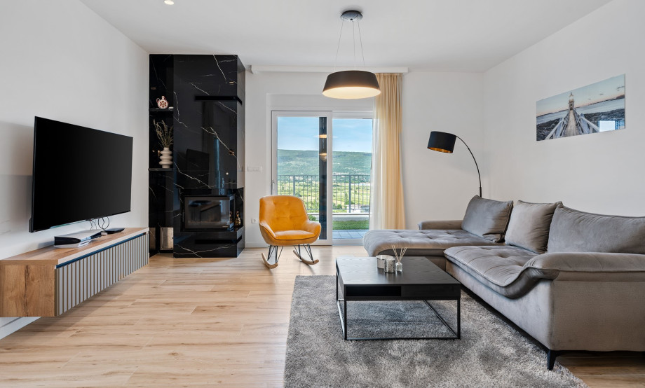 The elegantly furnished living room includes comfortable sofas, a TV, and air conditioning