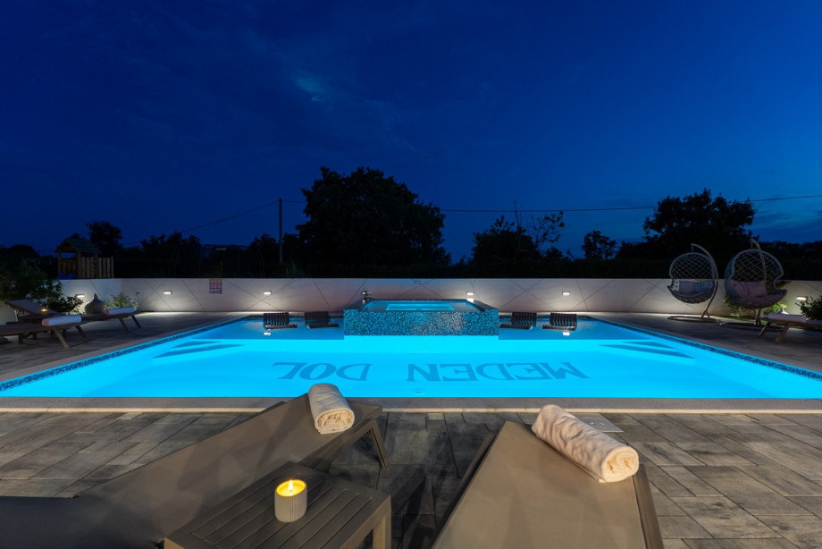9 x 6.5 meter heated pool with shallow sections and four partially submerged deck chairs