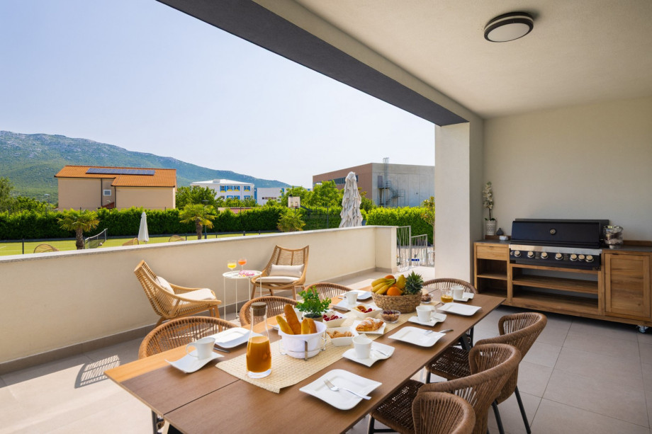 a covered outdoor dining area for 12 people with a barbecue (next to living and dining area at the ground floor level)