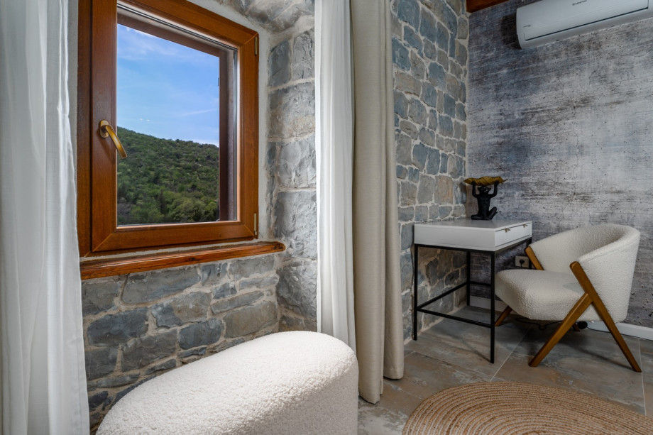 A stylish open-plan kitchen and living area with a window looking toward unspoiled nature.
