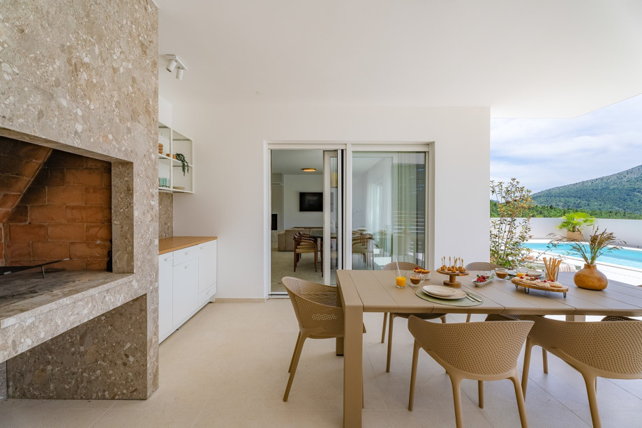 A covered dining area beckons guests to enjoy al fresco meals in style, complete with a summer kitchen