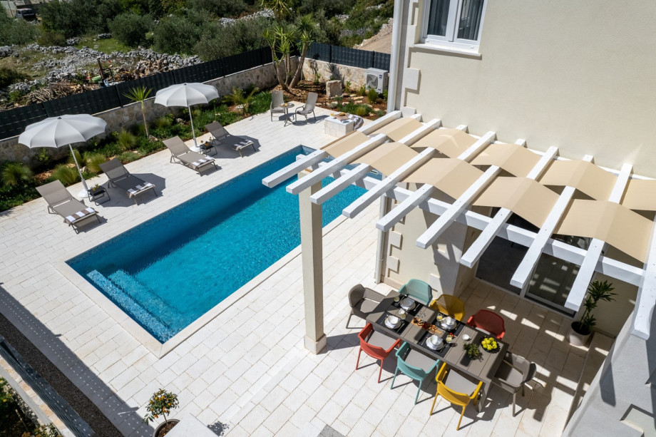 The outdoor dining area is next to the barbecue and heated pool.