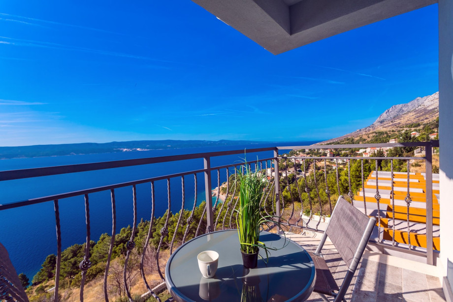 The private balcony offers a breathtaking, elevated view over the coastline and the expansive blue sea, perfect for quiet morning moments