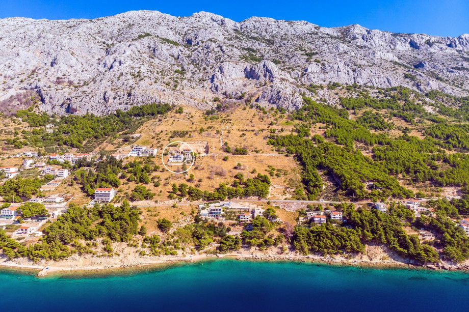 A broad aerial view emphasizes the isolated, prime location of the villa on the hillside, nestled beneath the imposing mountains