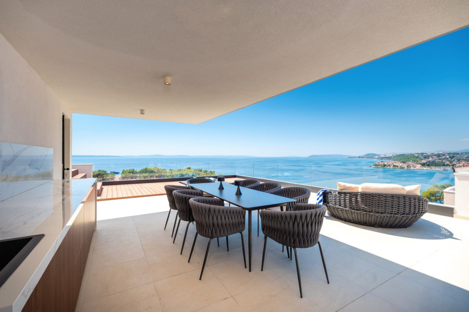 There is an outdoor dining area and a kitchen table with a sink and a refrigerator
