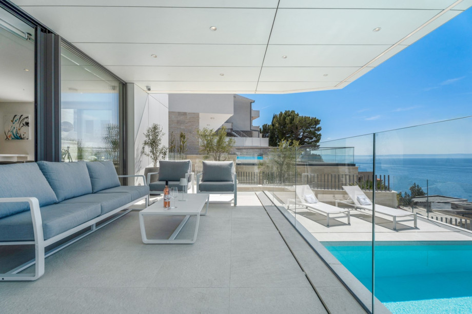 Few steps above the pool is a covered deck area with a lounge corner